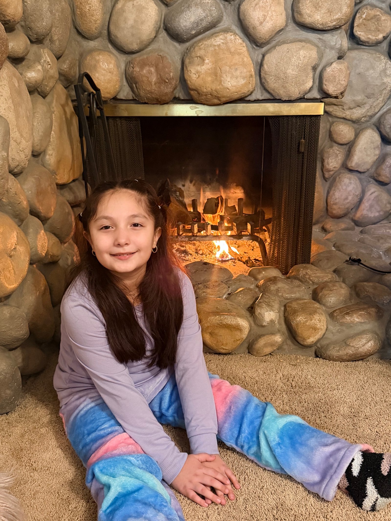 Foto real de niña junto a chimenea